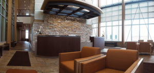 The soaring atrium is open and bright, characterized by it’s rich woodwork, walls of windows, and stacked stone walls. Patients are welcomed in this reception area by concierges who guide them to their doctor’s office.