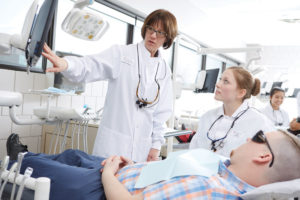A doctor assists a dental student.